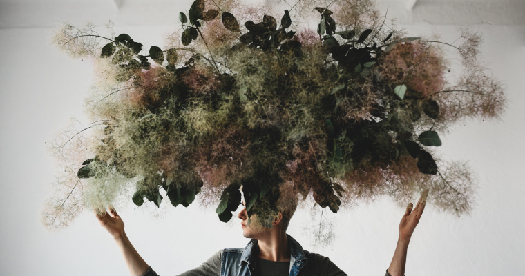 large decorative bouquet made green leaves moss hangs man s head