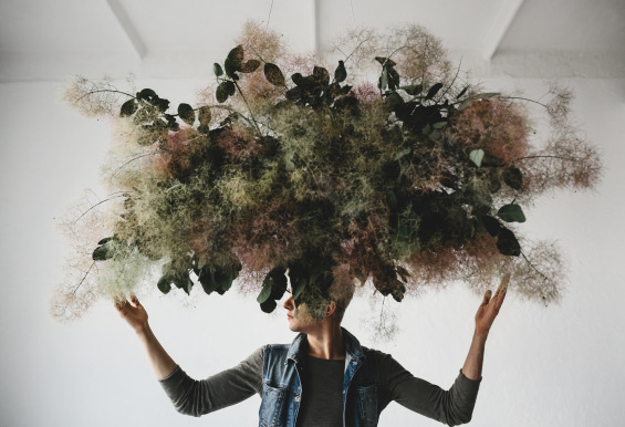 large decorative bouquet made green leaves moss hangs man s head