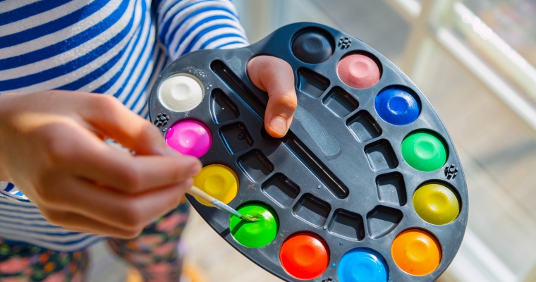 little kid painting with watercolour paint home school