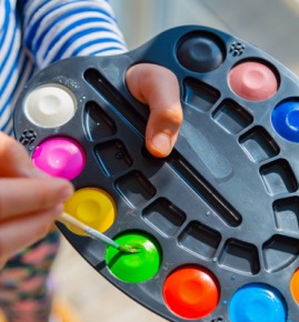 little kid painting with watercolour paint home school